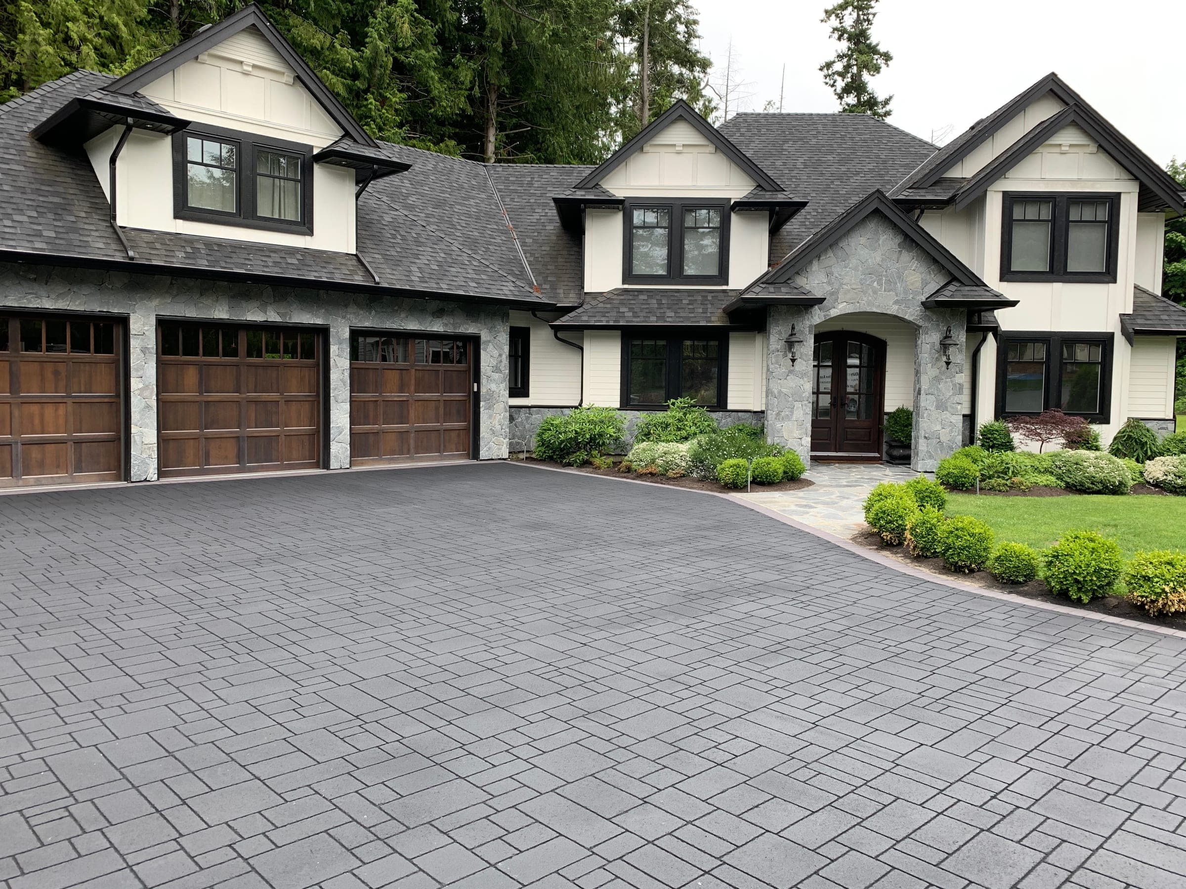 Grey ashlar slate StreetPrint stamped asphalt driveway in front of a three-car garage, installed by Square One